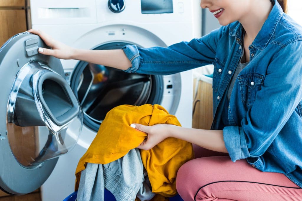 Woman loading clothes into a washing machine.