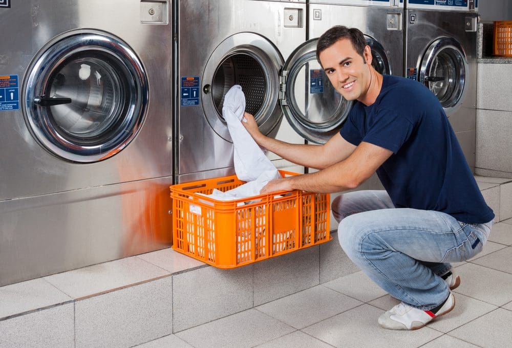 Young Man Putting Clothes In Washing Machine