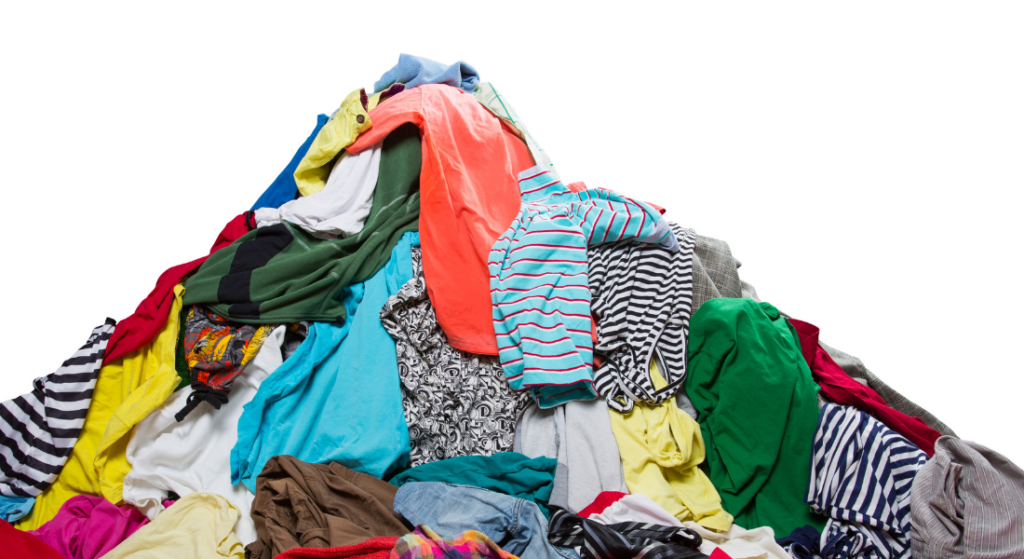 A large pile of various clothes in different colors and patterns, including shirts, jackets, and pants, scattered against a white background.